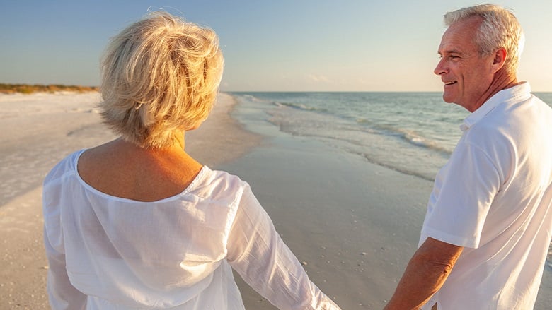 retired couple walking on beach