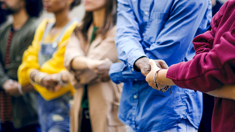 Group of people holding hand with sunglare behind