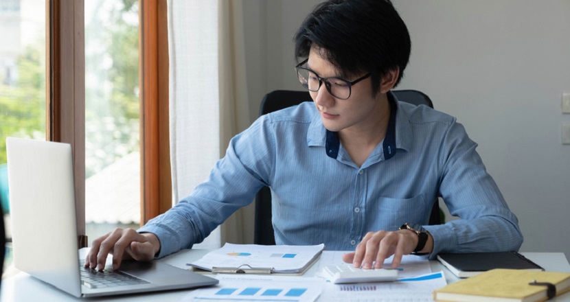 Man sitting behind desk with laptop and calculator