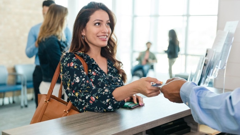 Woman hands her debit card to the bank teller