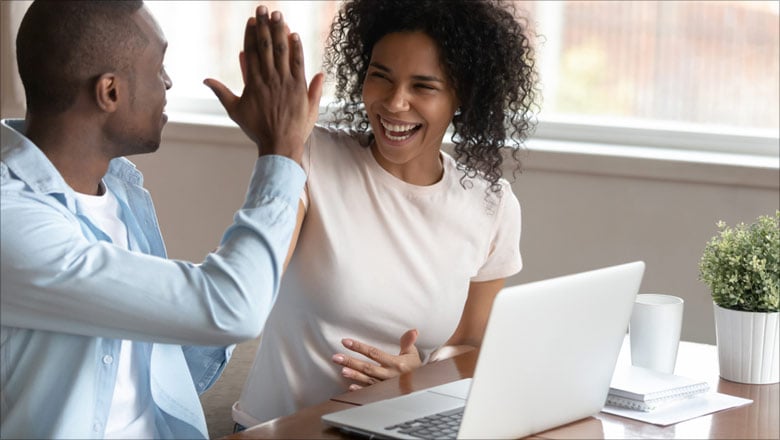 Couple high fiving at a laptop