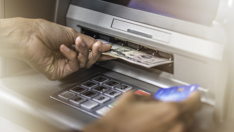 closeup view of hands removing money from ATM